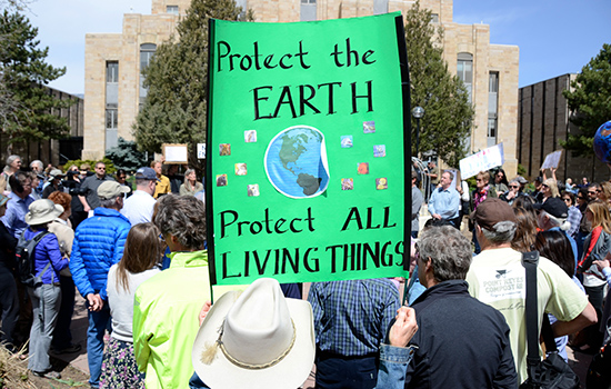 Local resident holds sign that says, "Protect the Earth, Protect All Living Things"