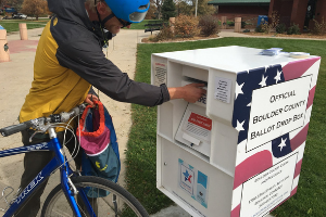 Man on bicycle dropping of his ballot at a 24-hour ballot drop box