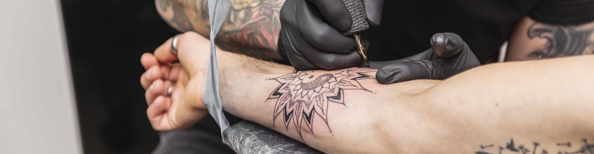 Tattoo master puts tattoo in form of flower on arm of another man