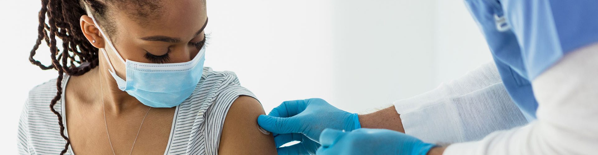 Woman looks down as nurse applies adhesive bandage