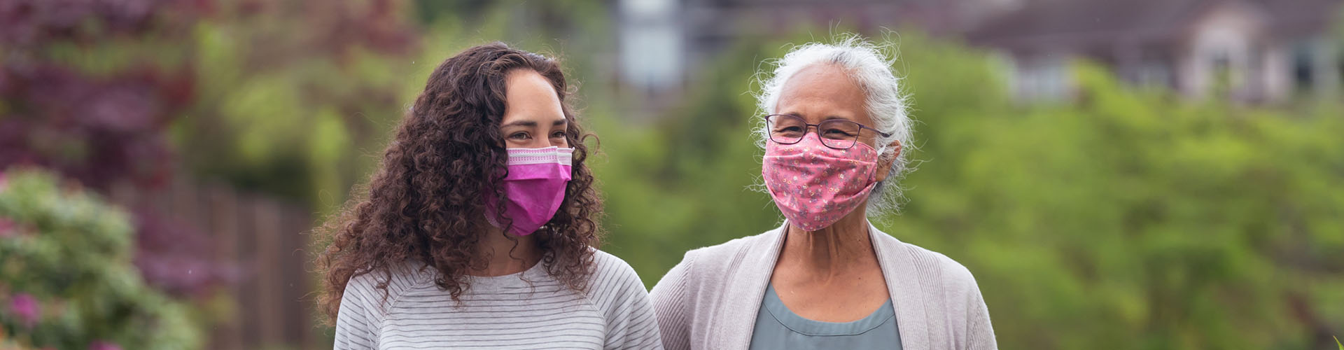 Senior woman and her adult daughter enjoying the outdoors together with masks on